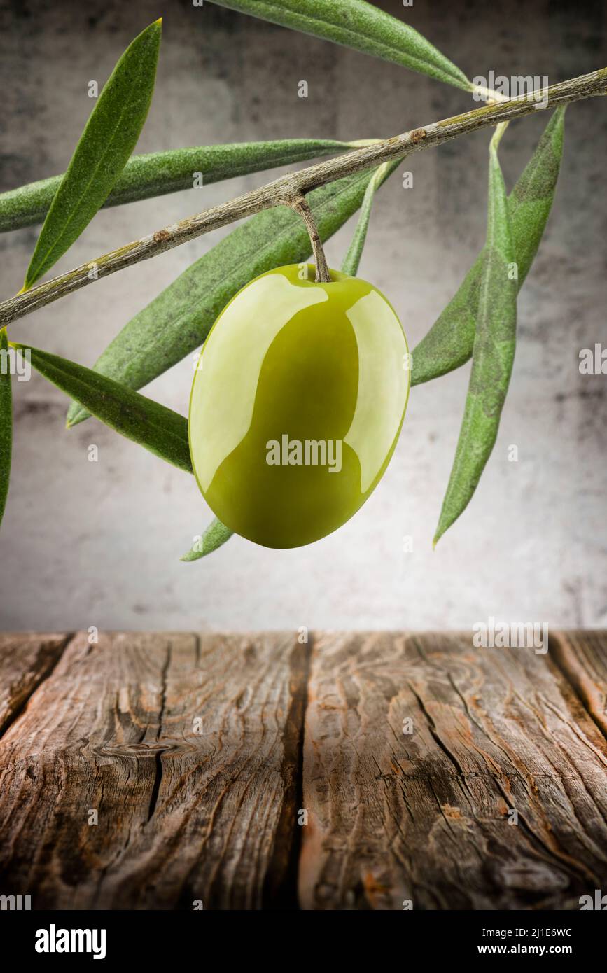 Grüne Olive mit Zweig und Blättern auf Holzgrund Stockfoto