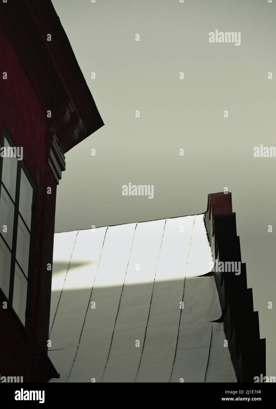 Schneebedecktes, sonnenbeschienes Dach und Fenster im Schatten, Gamla Stan, Stockholm, Schweden. Konzept von Geheimnis, Entführung, Gefangenschaft Stockfoto
