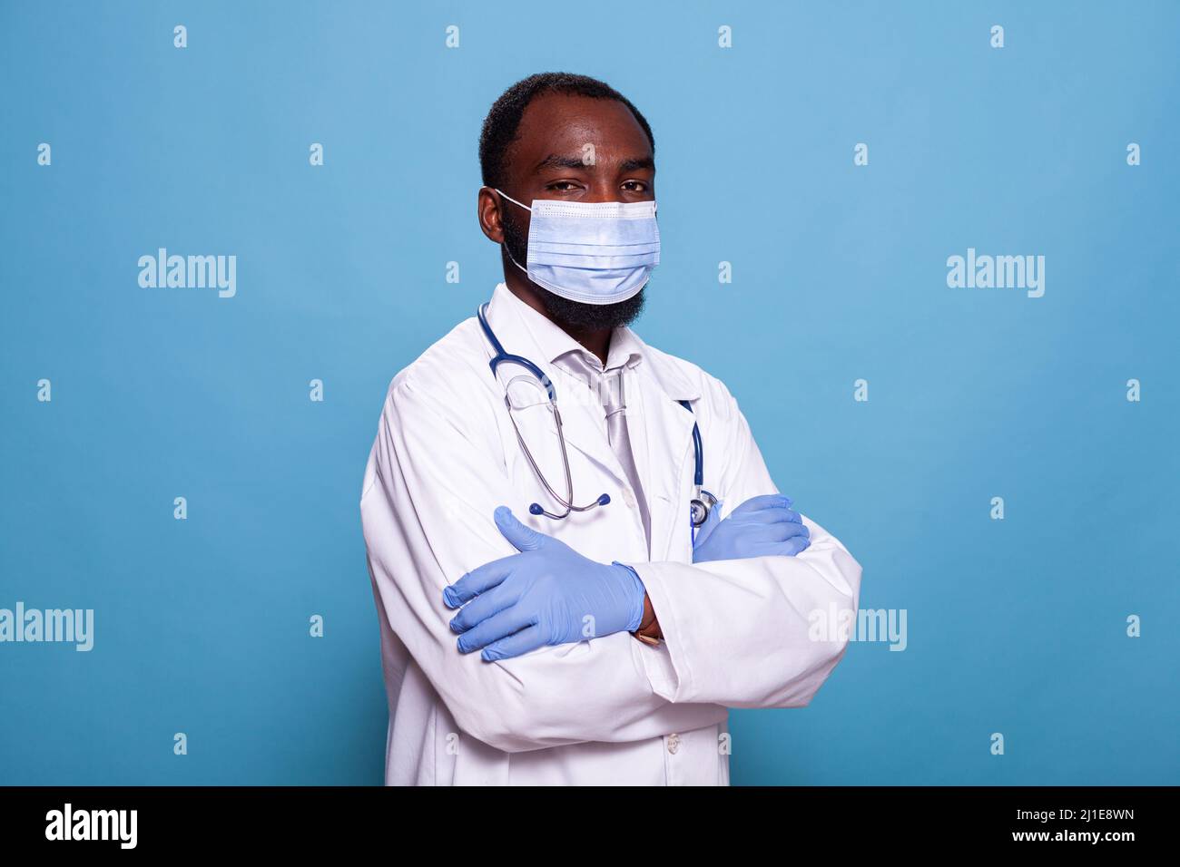 Porträt eines selbstbewussten Arztes mit Peelings mit Gesichtsmaske und Latexhandschuhen vor dem Gespräch. Medic mit Stethoskop und medizinischer Schutzausrüstung und weißer Laborkittel. Stockfoto