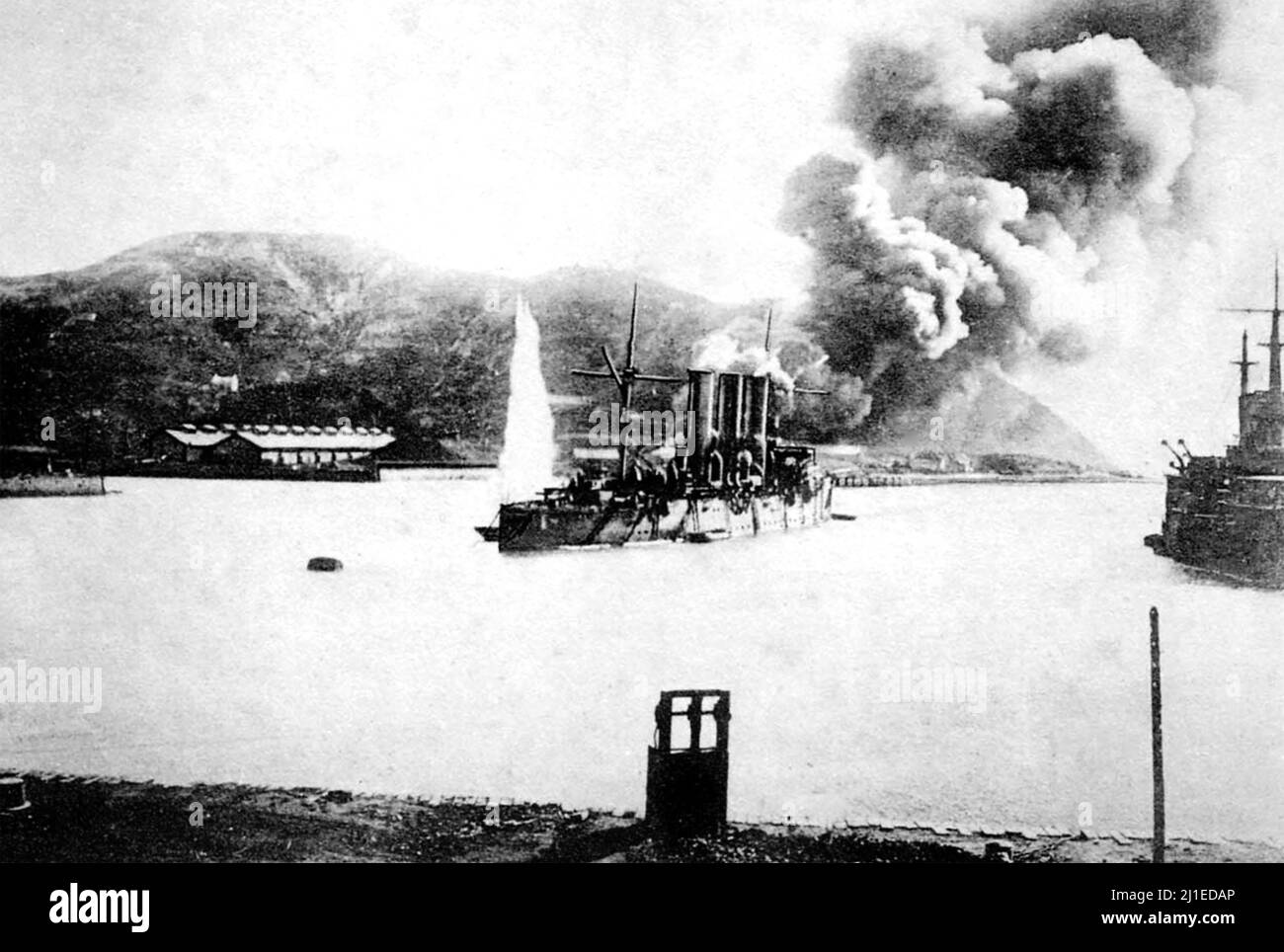 RUSSISCH-JAPANISCHER KRIEG 1904-1905. Der russische Kreuzer Pallada wurde im Februar 1904 in Port Arthur unter Beschuss genommen, während die Ölraffinerie im Hintergrund brennt. Stockfoto