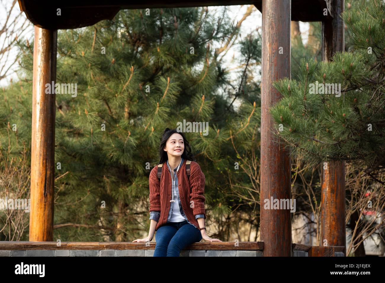 Junge chinesische Universitätsstudentin, die sich in einem Pavillon mit einem Stock-Foto entspannt Stockfoto