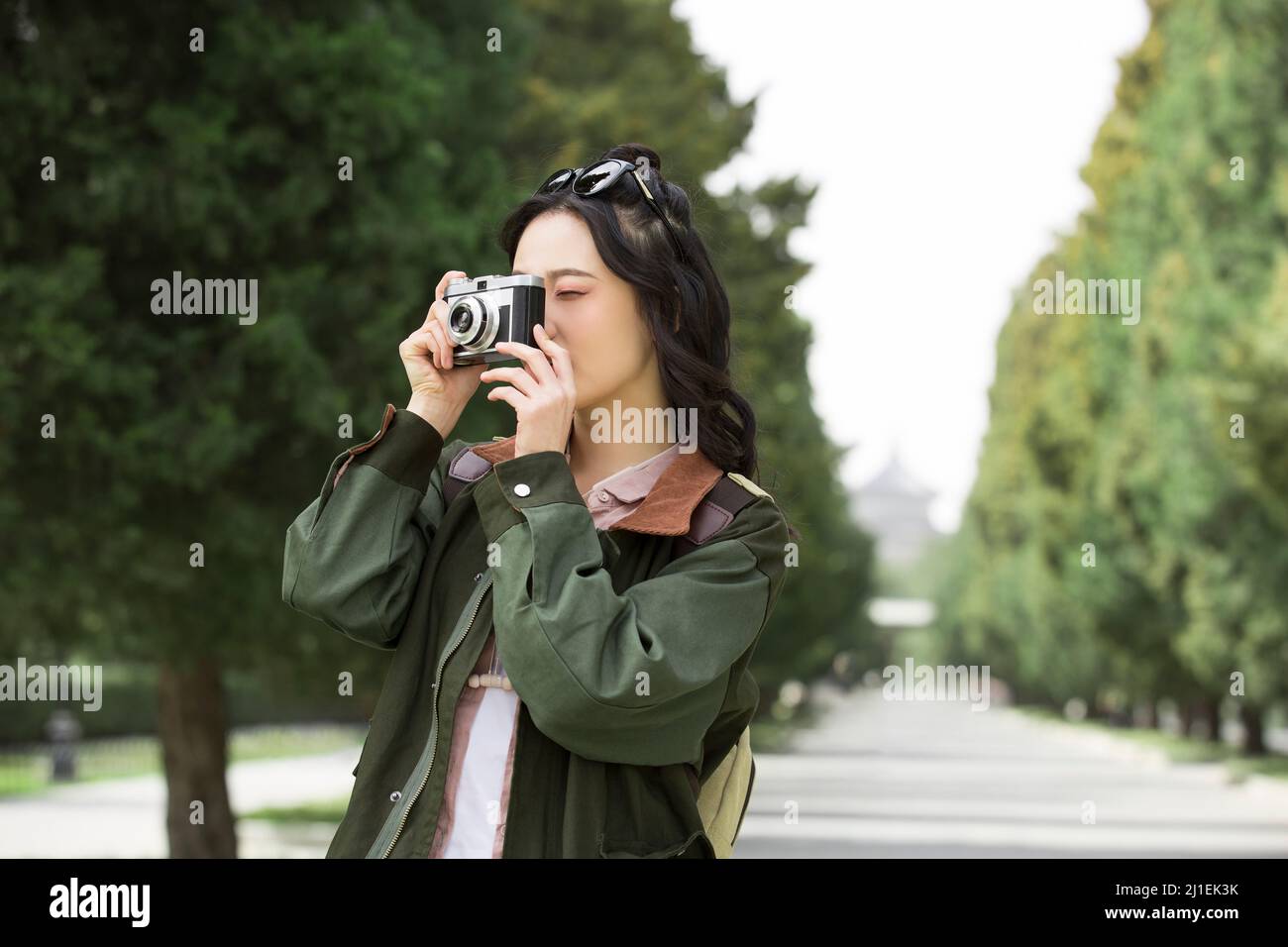 Junge weibliche Touristen, die Fotos in einem von Bäumen gesäumten Park machen - Stock Photo Stockfoto