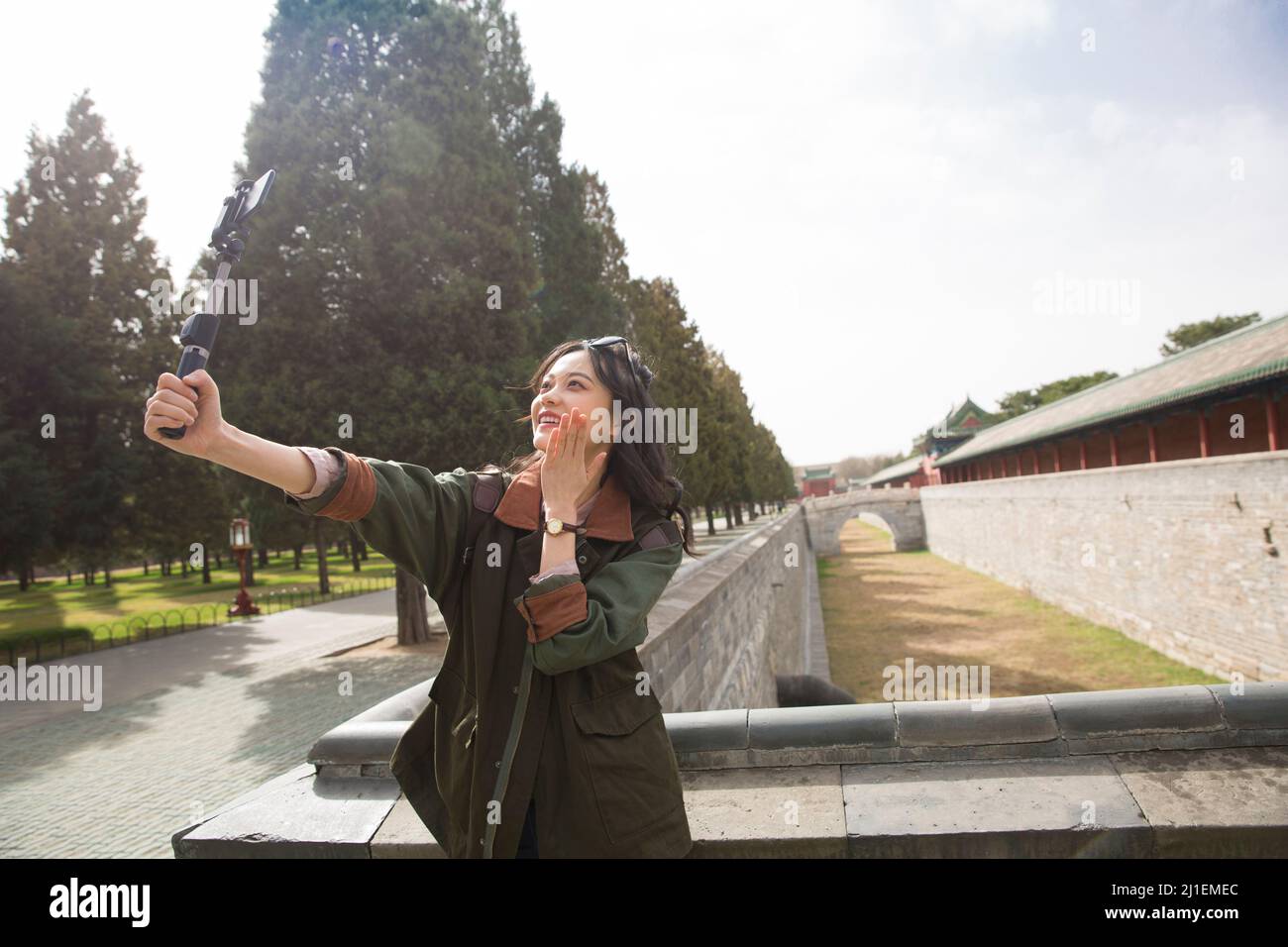 Junge weibliche Tourguide hält Selfie-Stick, um Live-Video auf Smartphone zu streamen - Stock Foto Stockfoto