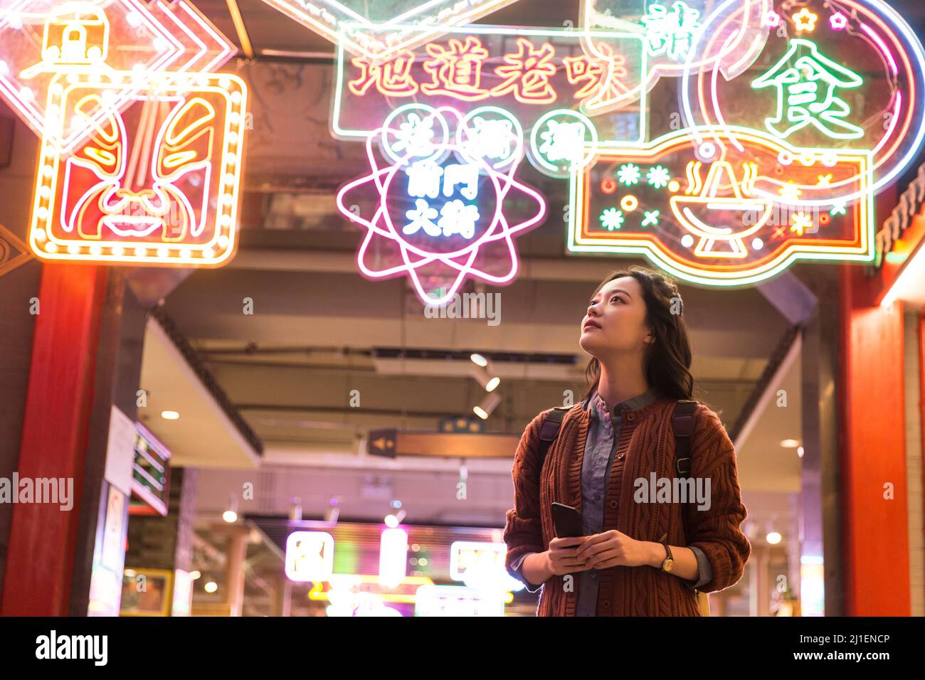 Junge weibliche Touristen genießen Landschaft unter Neonlichtern des Nachtmarktes - Stock Foto Stockfoto
