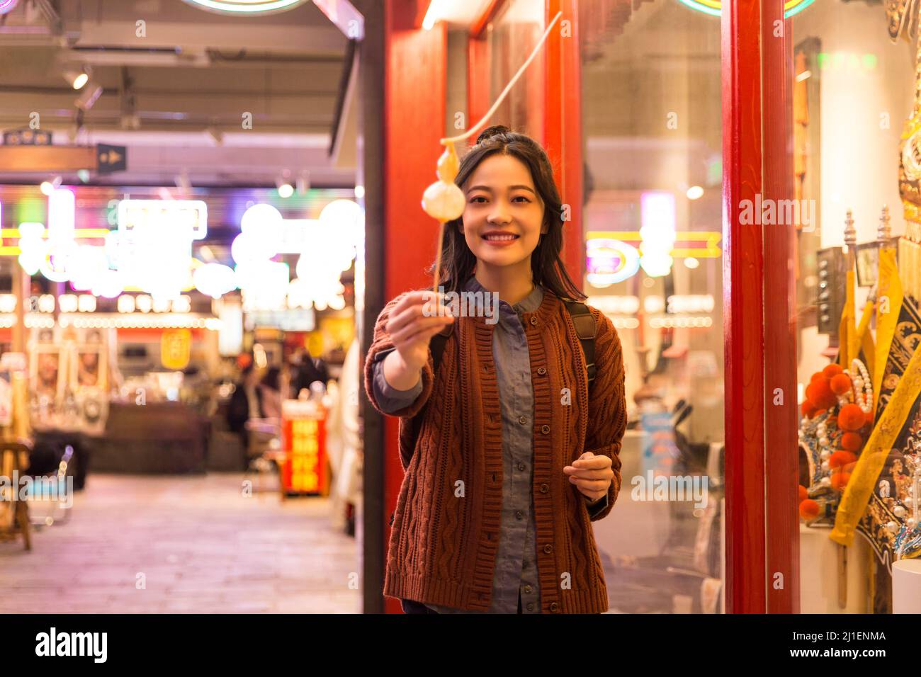 Lächelnde weibliche College-Studentin, die kalabaschförmige Zuckerfiguren mit der Kamera teilt - Stock-Foto Stockfoto