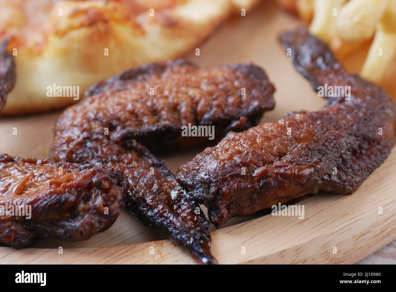 Hähnchenflügel und Pizza auf Holzplatte auf dem Tisch Stockfoto