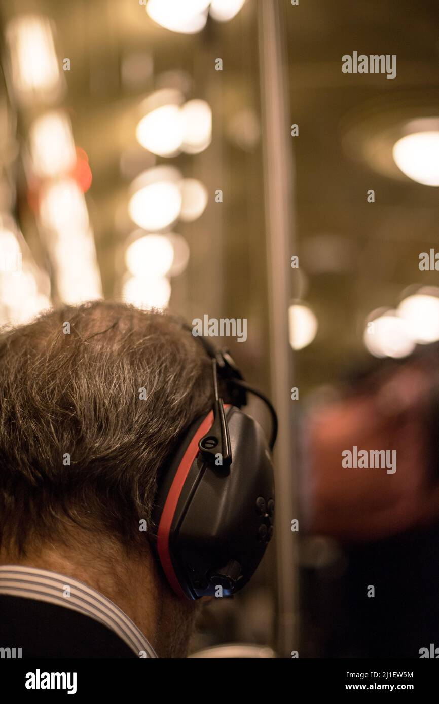 Konzept der Lärmbelästigung in den Städten.ein alter Mann in geräuschreduzierenden Kopfhörern mit Bookeh-Hintergrund. Stockfoto