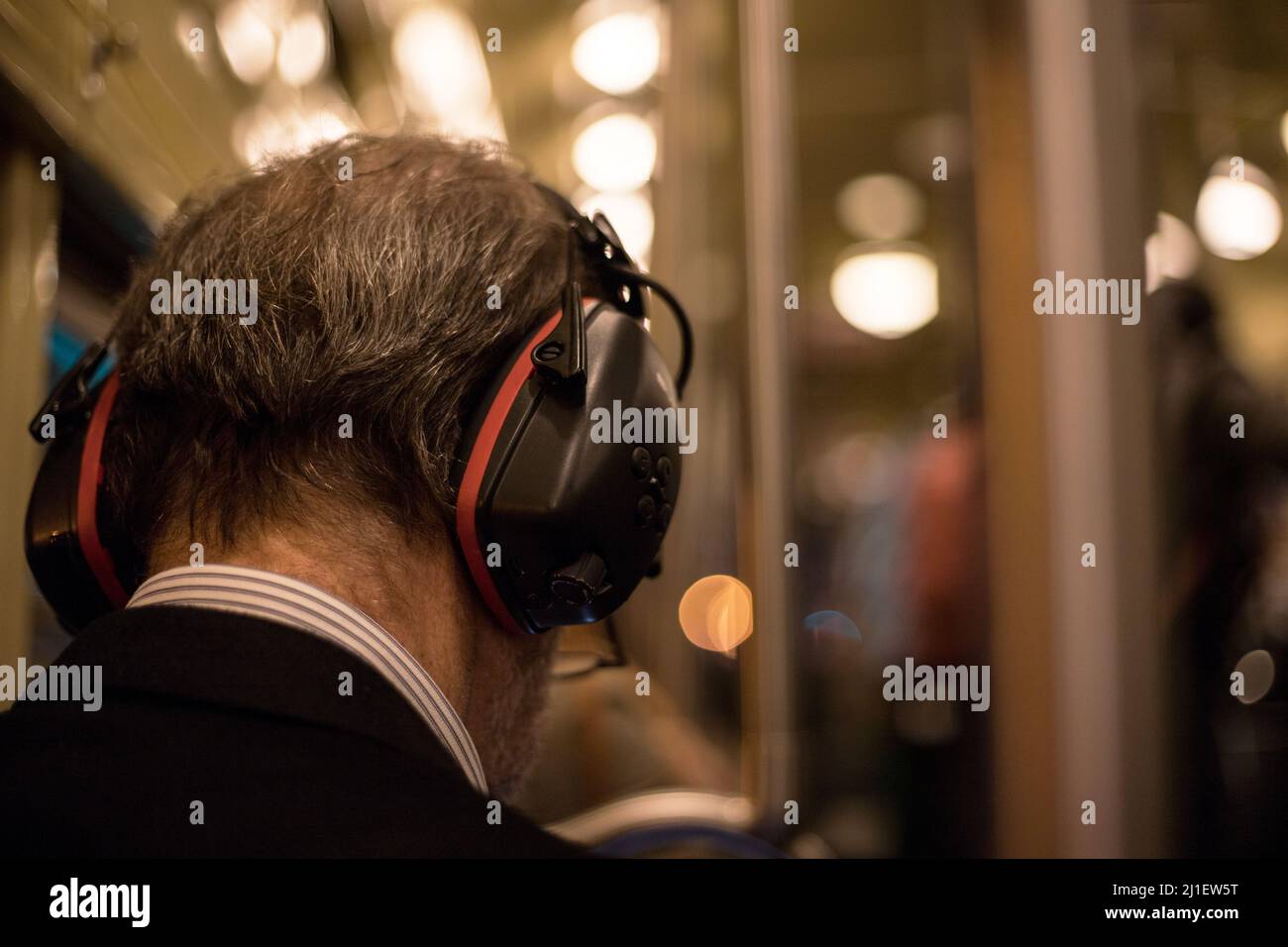 Ein Mann mit geräuschreduzierenden Kopfhörern in einem Bus. Konzept der Lärmbelästigung in den Städten. Stockfoto