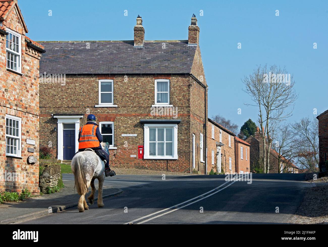 Mann, der am Straßenkreuzung im Dorf Crayke, North Yorkshire, England, reiten kann Stockfoto