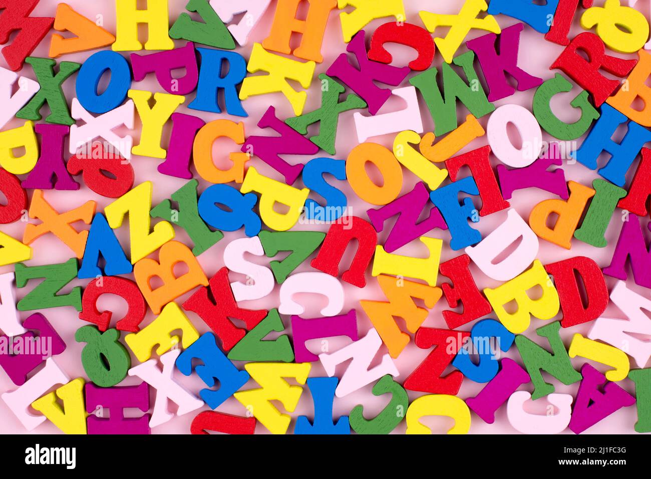 Bunte helle Holzbuchstaben auf rosa Hintergrund. Zurück zum Schulkonzept. Stockfoto