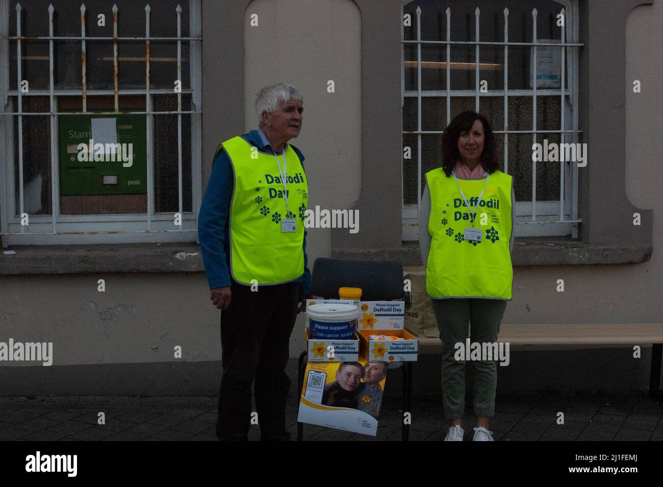 Bantry, West Cork, Irland, Freitag, 25. März 2022; die Sonne schien heute auf dem Bantry Market und zog die Menschen aus. Viele Leute waren in T-Shirts mit Temperaturen von 22 Grad. Die Freiwilligen Susan O'Donovan und Jerry Sheehan verkaufen Narzissen für die Irish Cancer Society im Bantry Post Office. Credit ED/Alamy Live News Stockfoto