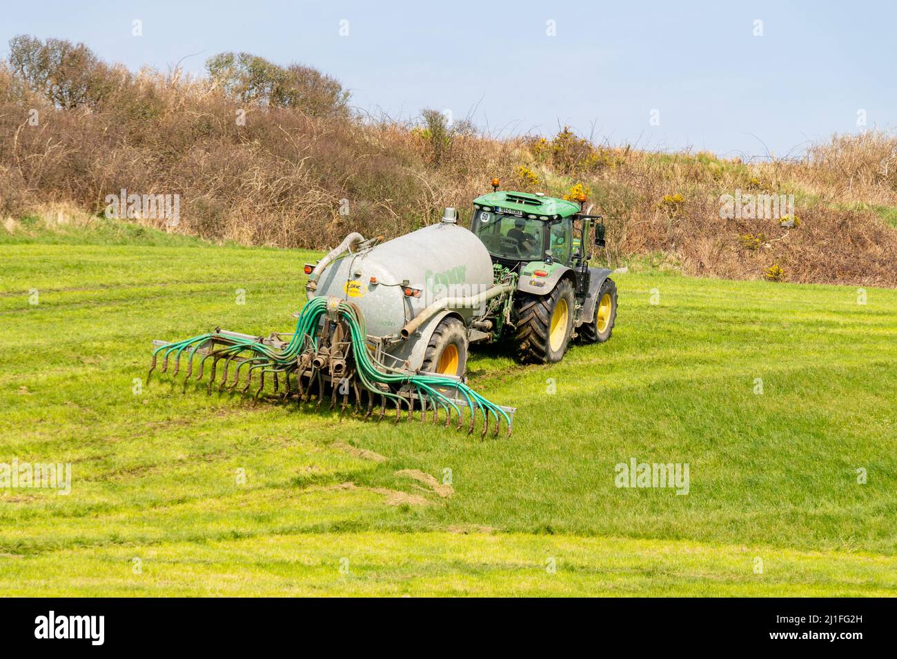 Gülle, die sich mit Tropfstangen ausbreitet, die vom Traktor auf der irischen Farm abgeschleppt werden Stockfoto