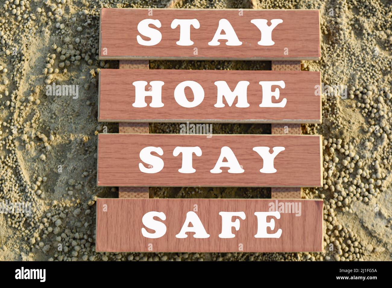 Bleiben Sie zu Hause Bleiben Sie sicher Text auf Holzrahmen am Sandstrand. Pandemiekonzept. Stockfoto