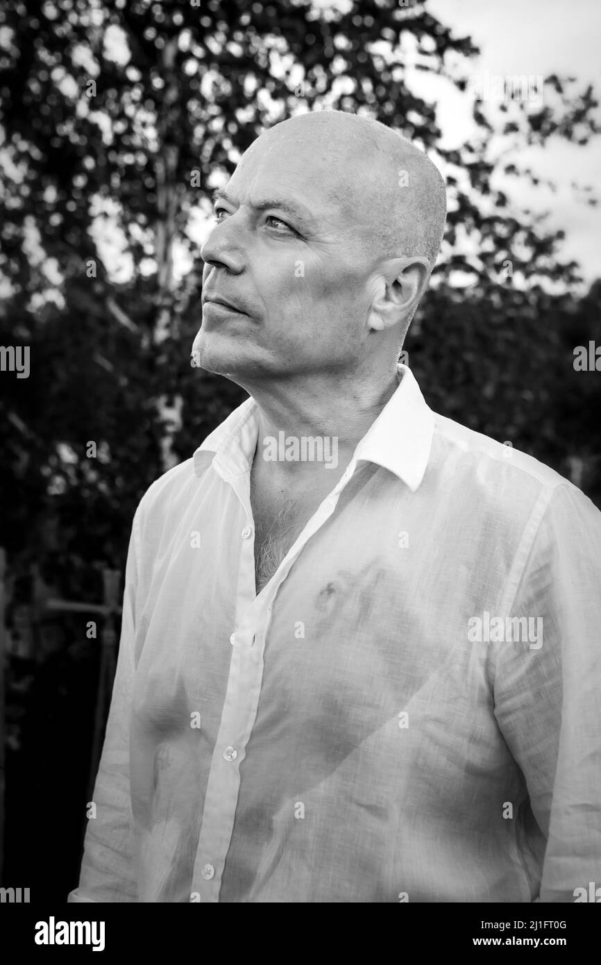 Porträt eines schönen Mannes im Freien mit nassem Hemd. Monochromes Foto. Stockfoto