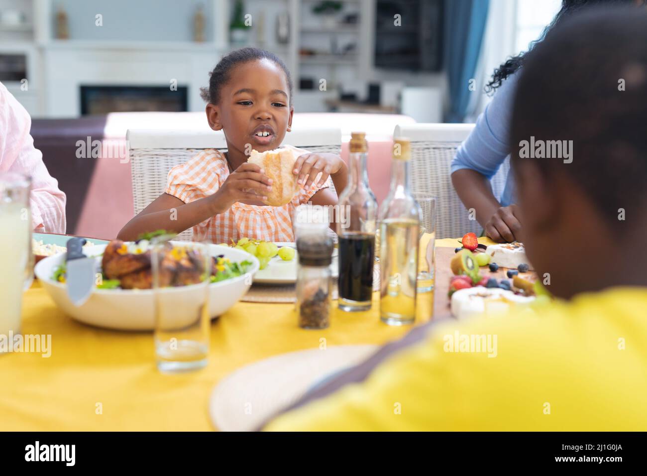 Nettes afroamerikanisches Mädchen, das mit der Familie zu Hause am Danktag zu Mittag gegessen hat Stockfoto