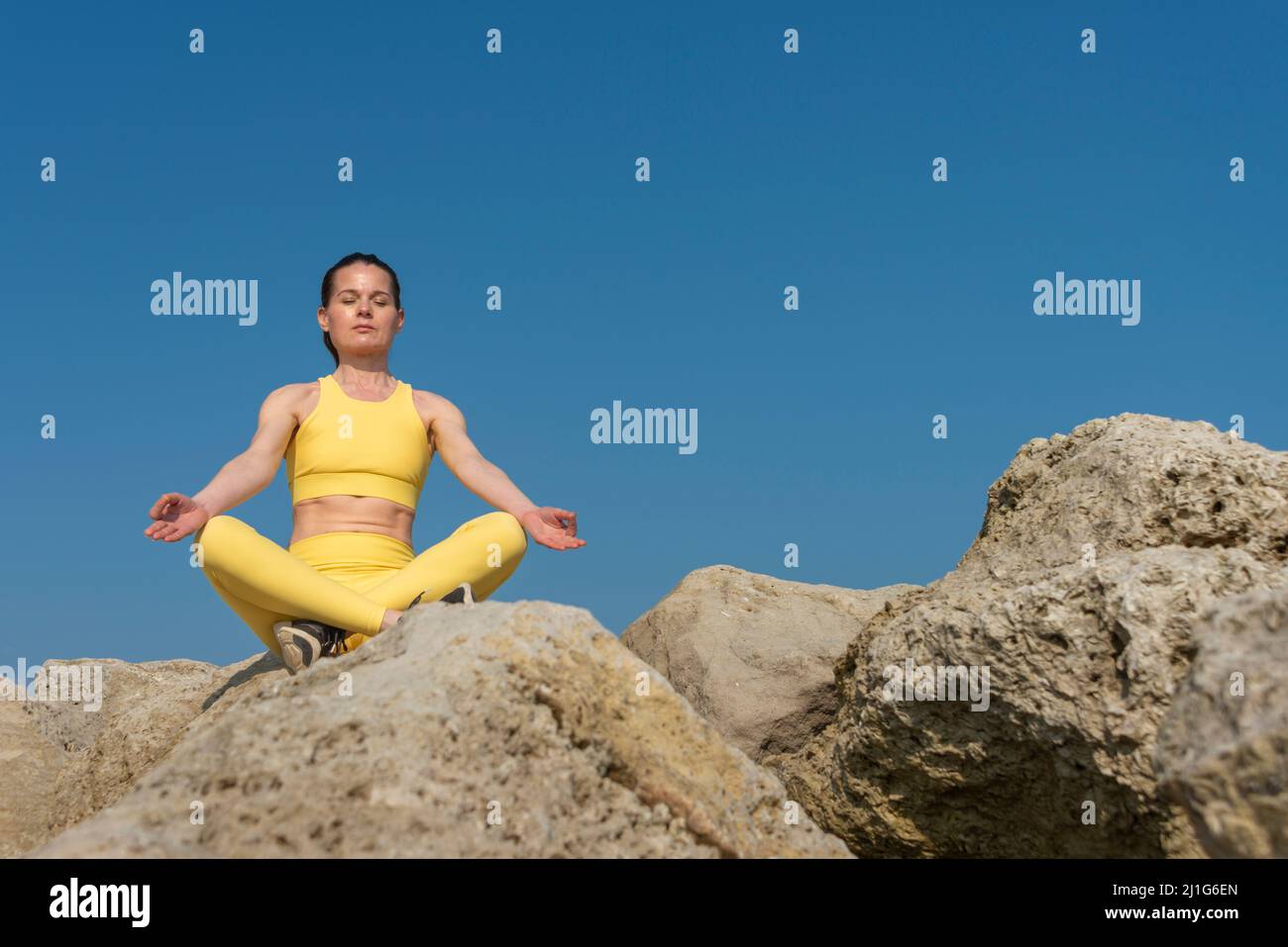 Frau, die Yoga-Meditation macht, sitzt auf Felsen. Gesunder Körper und Geist. Stockfoto