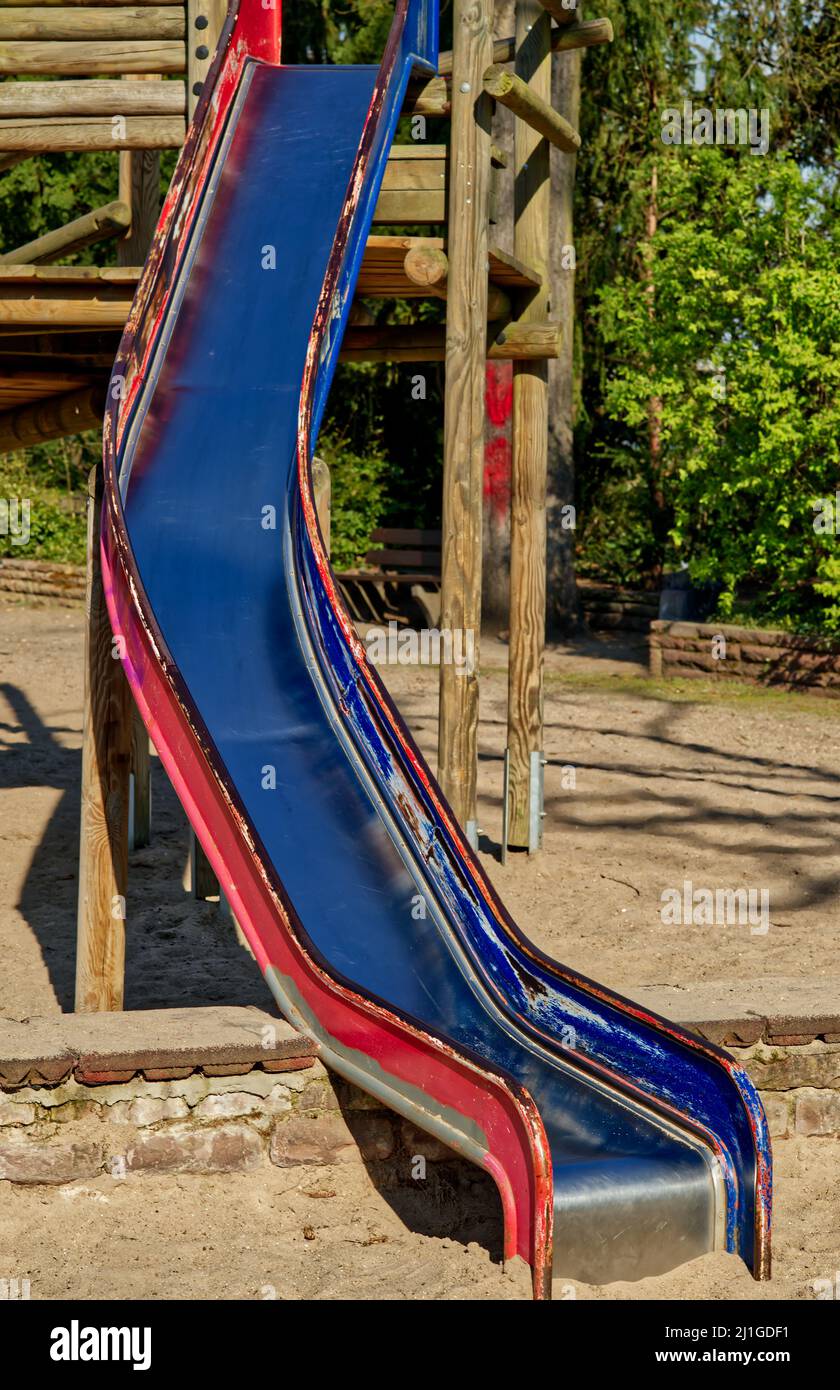 Spielplatzrutsche in blau und rot mit Sand auf einem Spielplatz Stockfoto