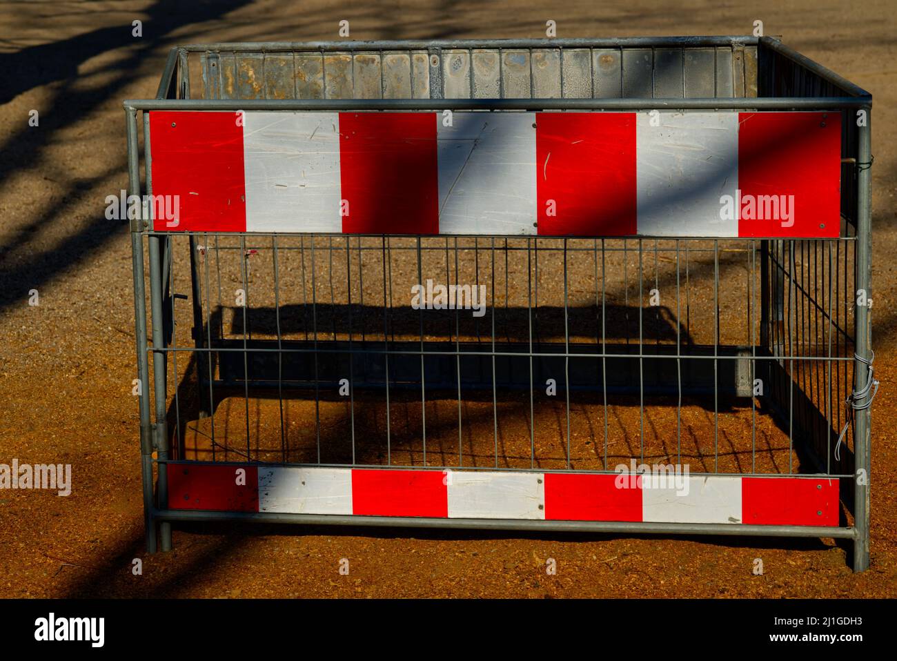 Kleiner Bauzaun in rot-weißen Streifen auf einem Spielplatz in der Sonne Stockfoto