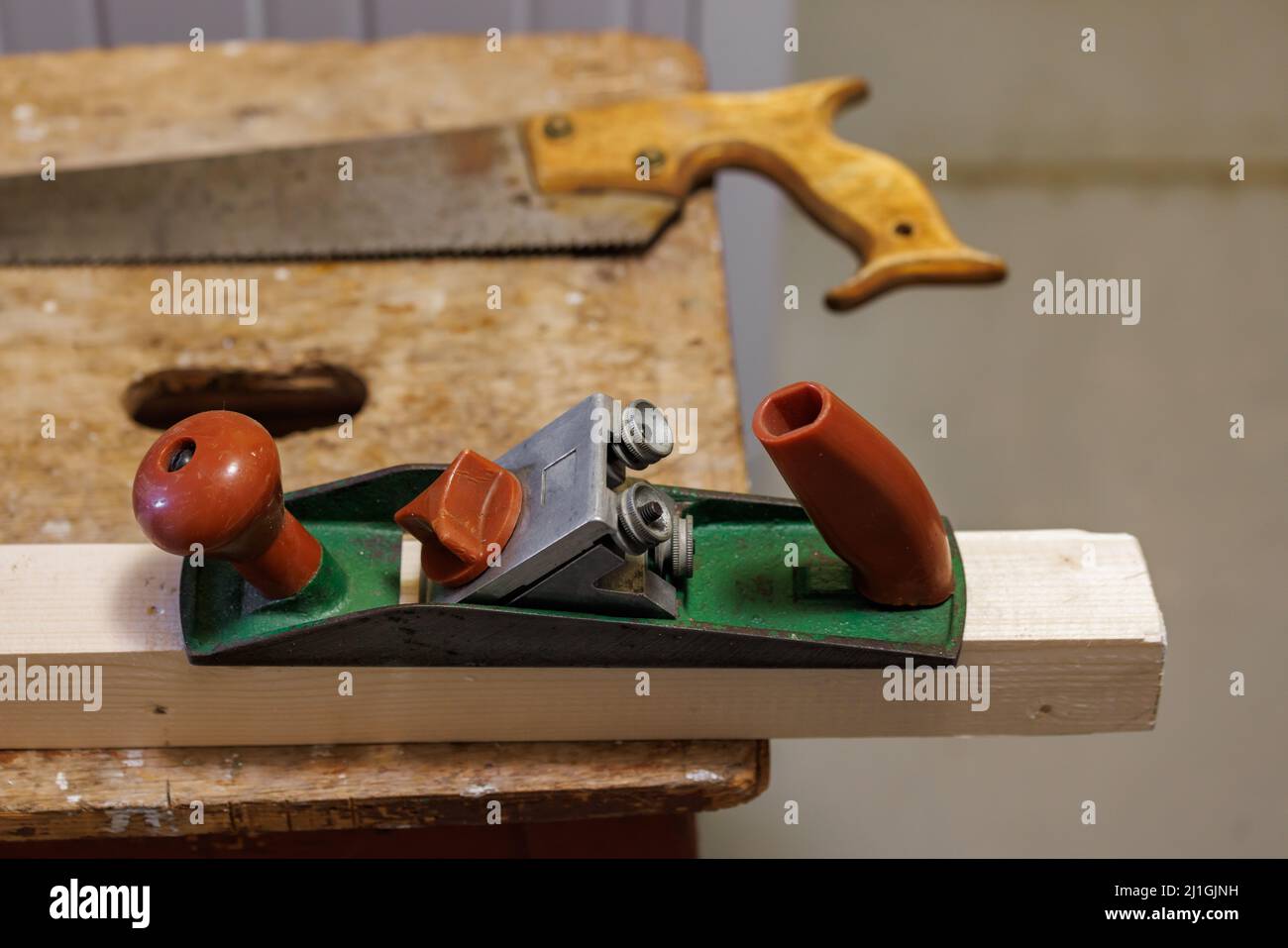 Hobel, Säge und Holzblock auf einem Hocker Stockfoto