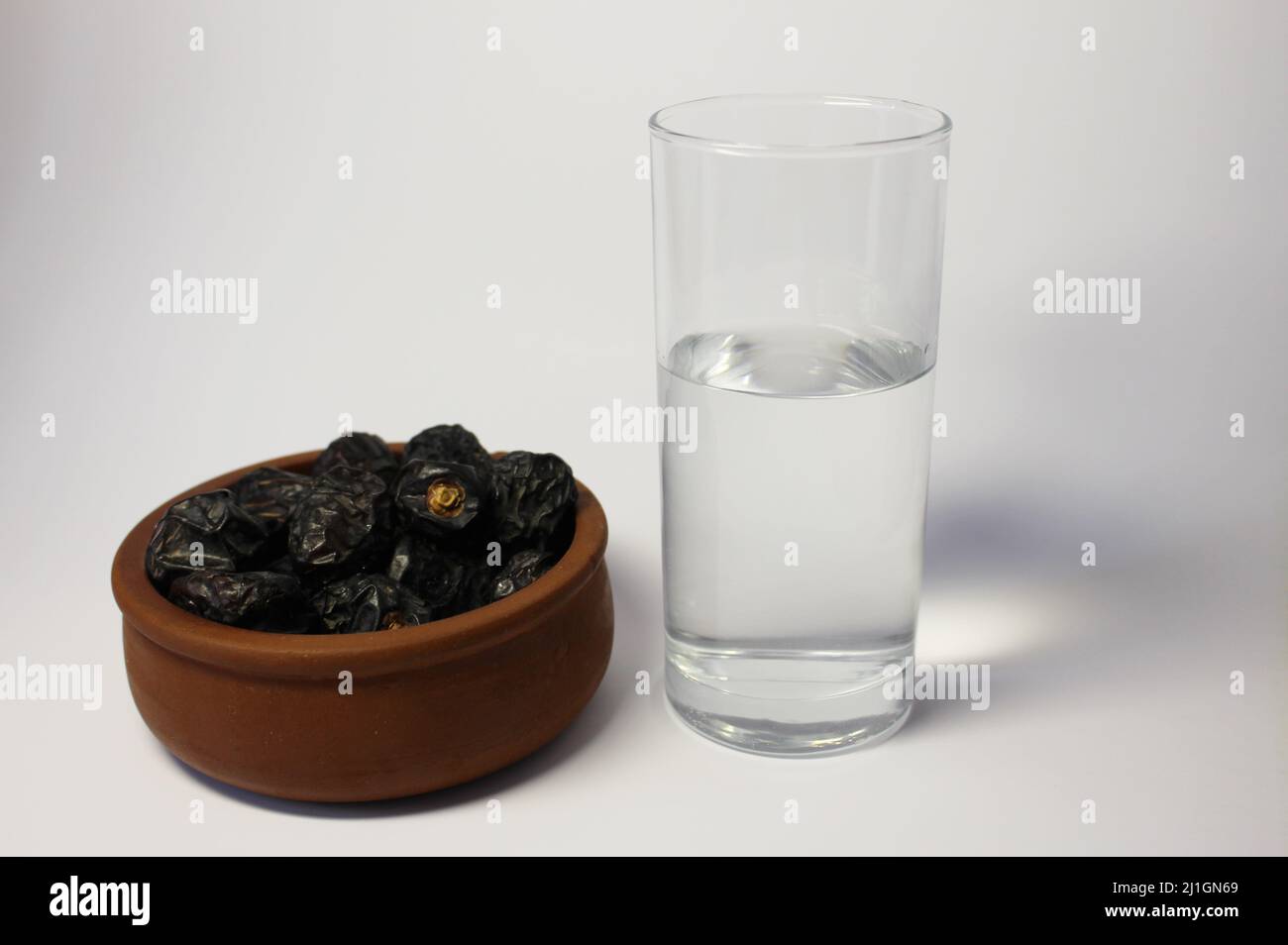 Ramadan-Konzept. Süße und nahrhafte Dataminfrüchte und ein Glas Wasser Stockfoto