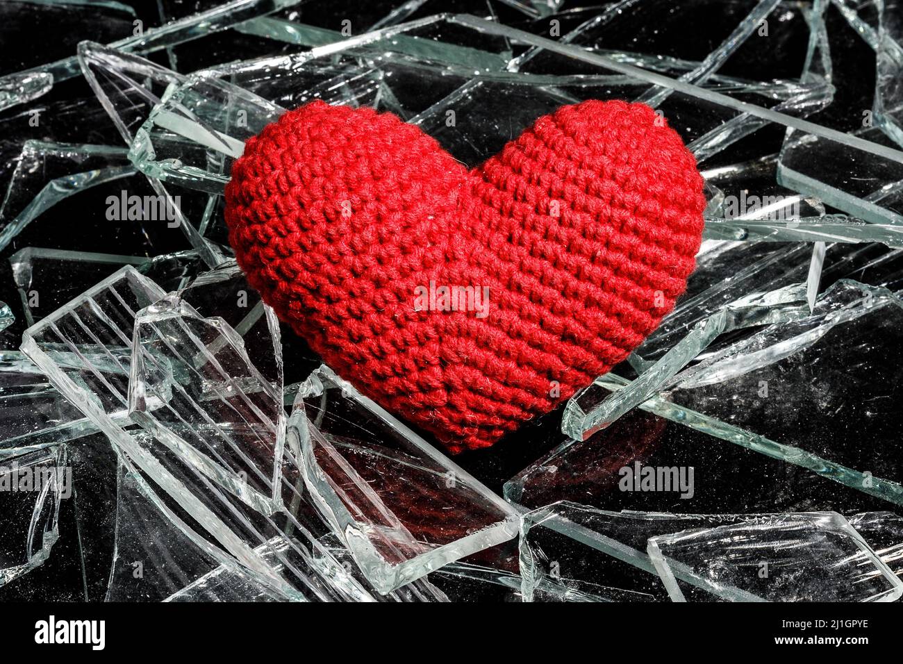 Rot gestricktes Herz auf Glasscherben. Hochwertige Fotos Stockfoto
