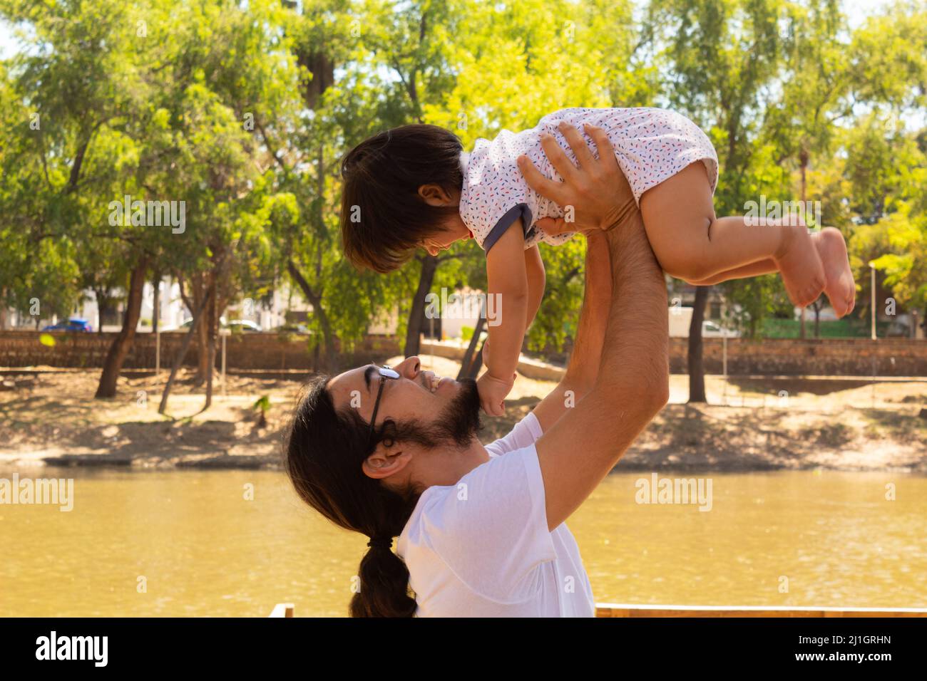 Porträt eines jungen hispanischen Vaters mit seinem Sohn in einem Park, der Spaß hat Stockfoto