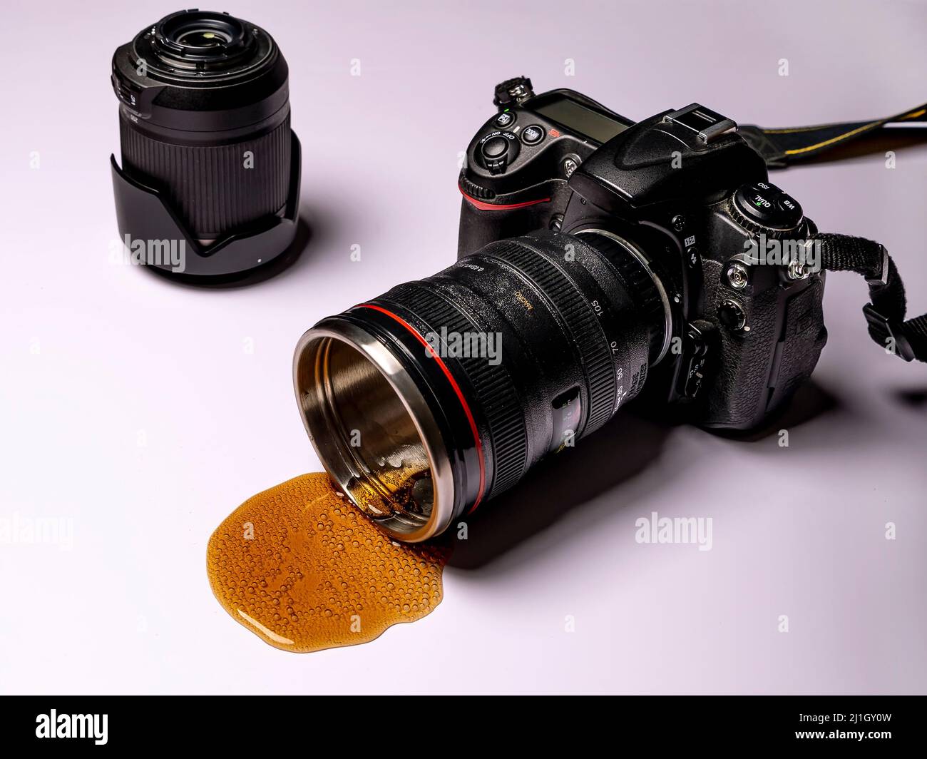 Cola kommt aus einem Objektiv einer professionellen Kamera mit einem anderen Objektiv in der Nähe, auf weißem Hintergrund Stockfoto