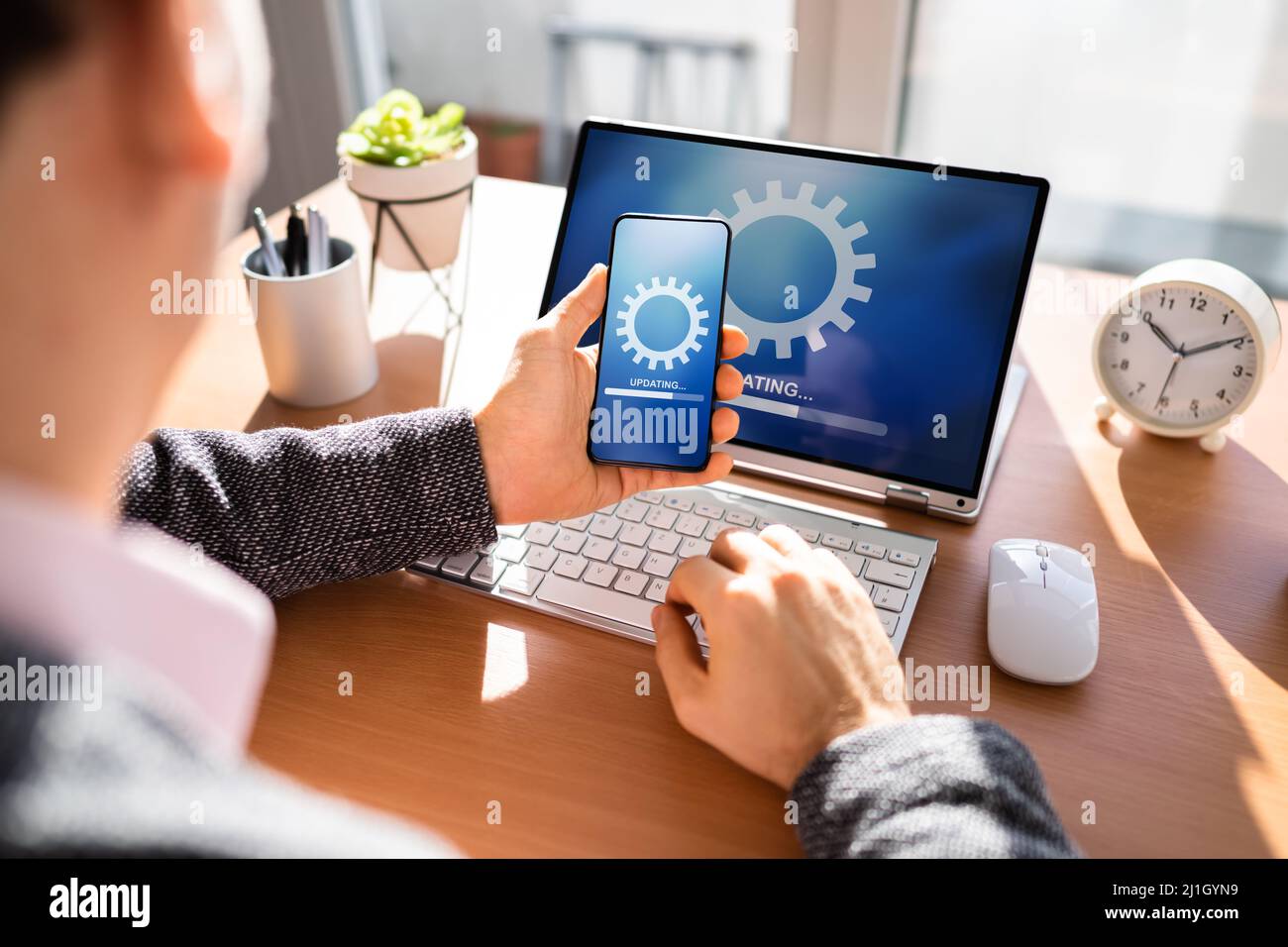 Mann, Der Software-Update Auf Mobiltelefon Und Laptop Macht Stockfoto