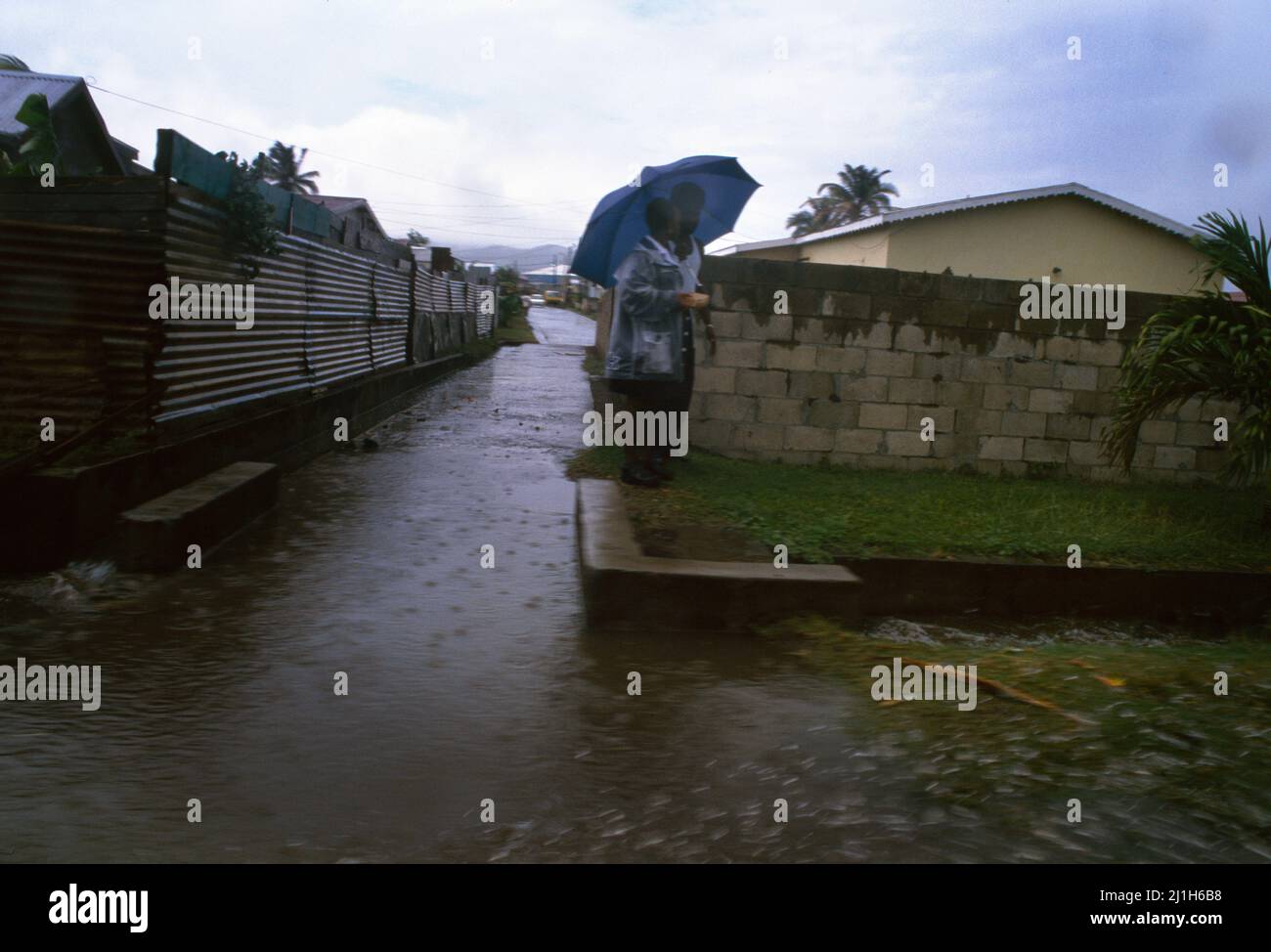 St. Kitts gehen in Monsoon zusammen mit dem Regenschirm spazieren Stockfoto