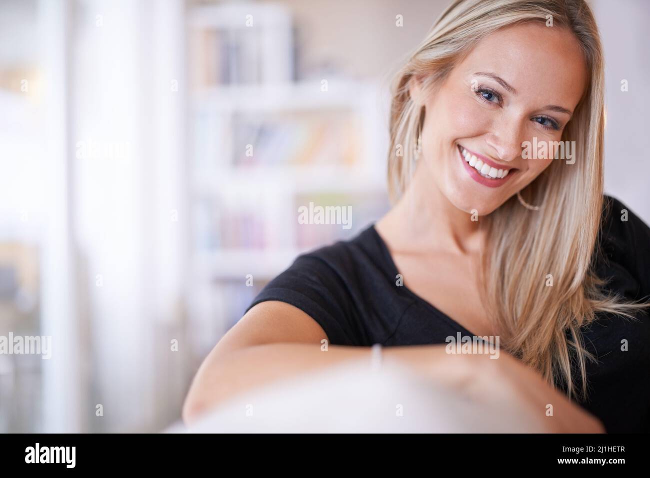 Zu Hause lasse ich meine Haare runter. Porträt einer jungen blonden Frau, die zu Hause auf ihrem Sofa sitzt. Stockfoto
