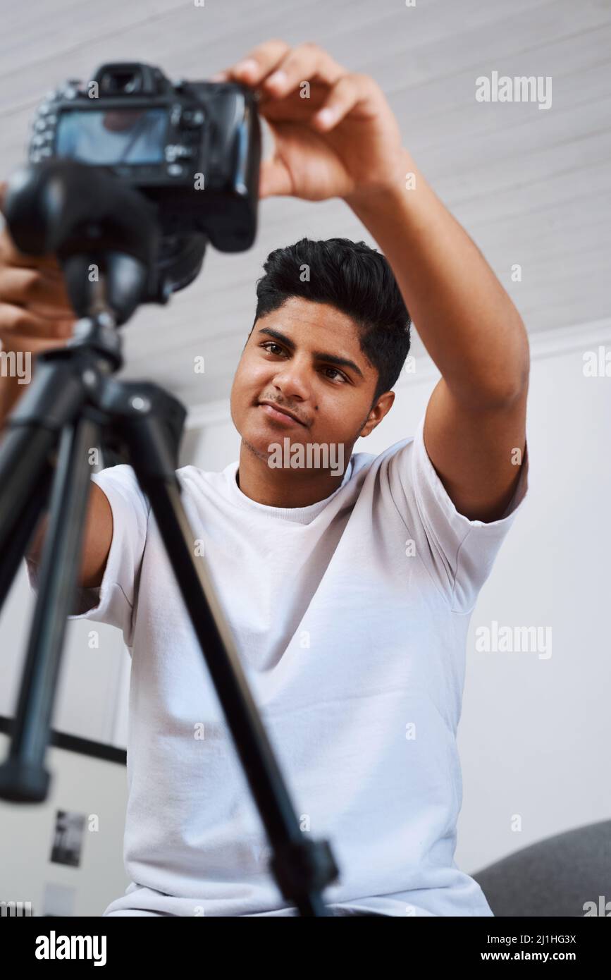 Ich habe mein Skript auswendig gelernt und bin bereit für den Weg. Ausgeschnittene Aufnahme eines jungen Mannes, der eine Kamera auf einem Stativ benutzte, um sich selbst zu Hause aufzunehmen. Stockfoto