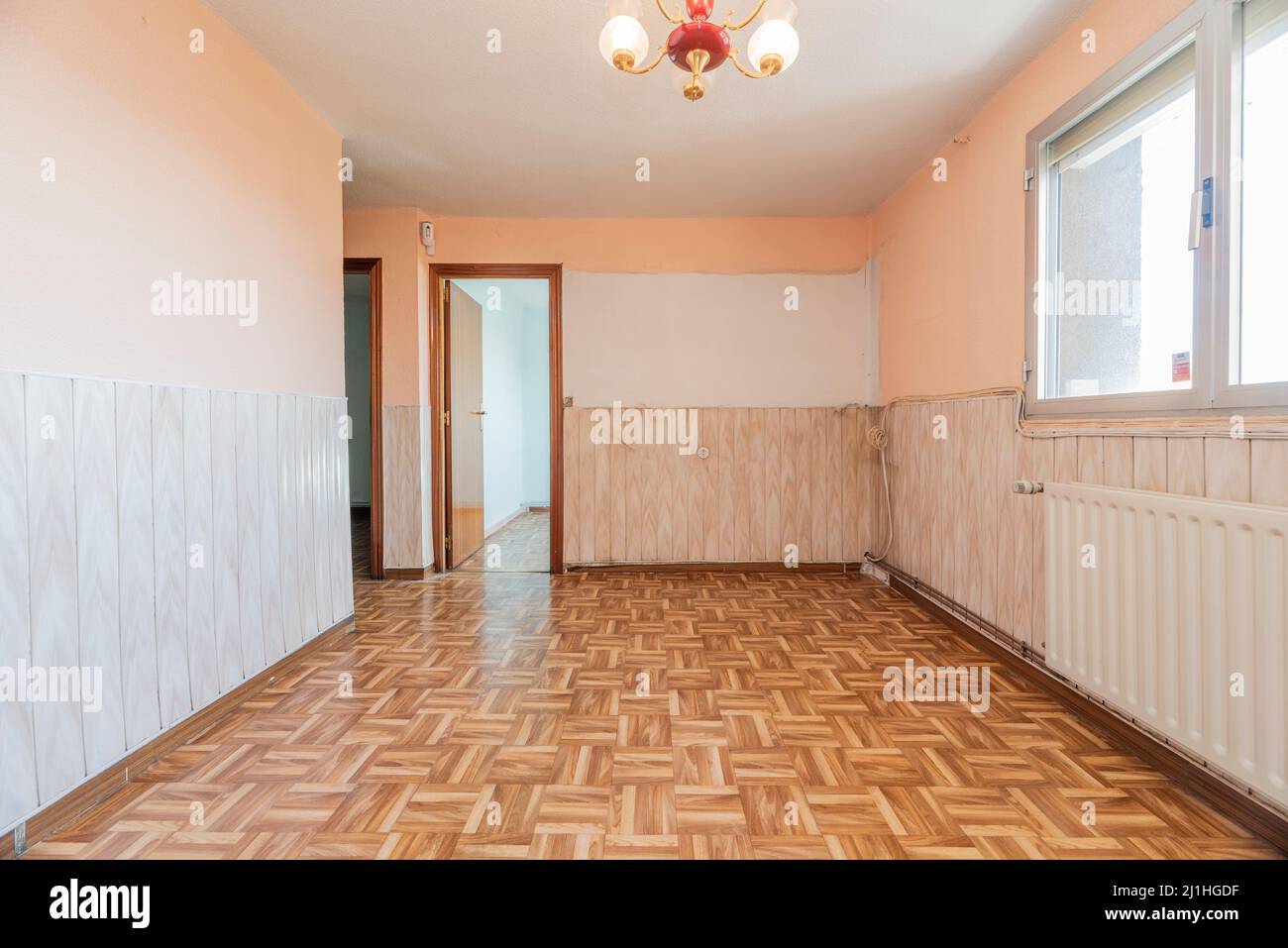 Leeres Wohnzimmer mit kitschigen Vintage-Dekor und Materialien und lackierten Holztüren, Halbwandfries und weißem Aluminiumheizkörper Stockfoto
