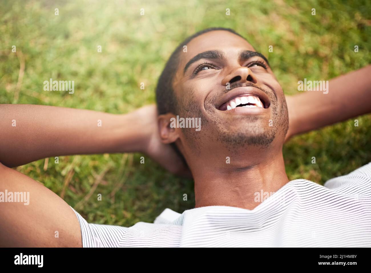 Egal, was Sie tun, machen Sie es großartig. Aufnahme eines jungen Mannes, der sich im Freien auf dem Gras entspannt. Stockfoto