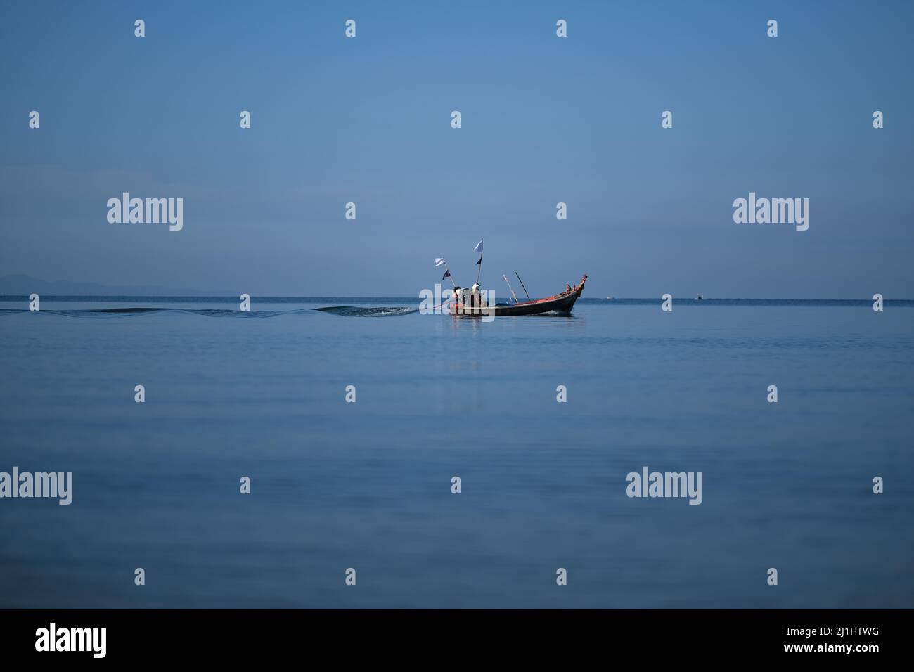 Ein Motorboot seziert das ruhige Meer und hinterlässt einen perfekten, wirbelnden Pfad Stockfoto