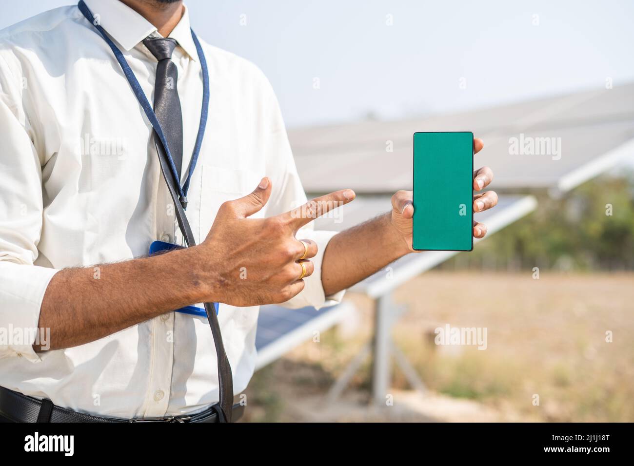 Hände zeigen Green-Screen-Handy durch Zeigen mit dem Finger vor dem Solarpanel - Konzept der Anwendungsförderung, Buchungsservice und Stockfoto