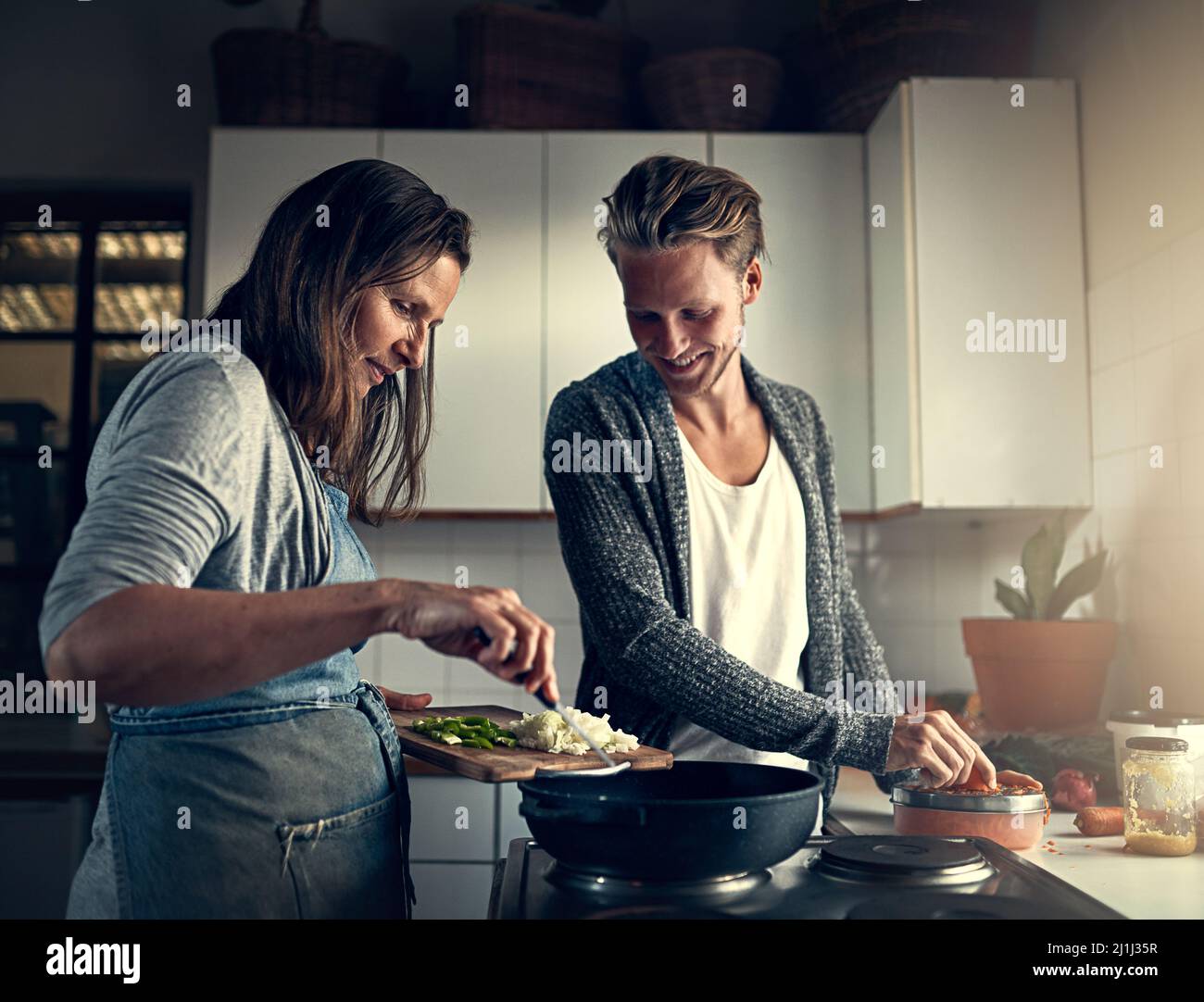 Etwas Besonderes zubereiten. Aufnahme einer Mutter und ihres erwachsenen Sohnes, die zu Hause in ihrer Küche kochen. Stockfoto