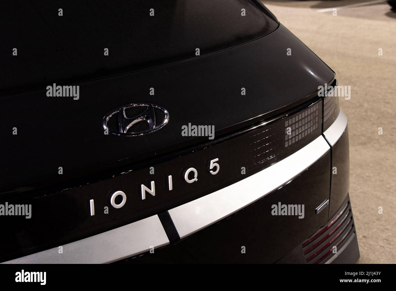 Auf der Rückseite eines schwarzen Autos in der Nacht ist ein IONIQ 5-Emblem zu sehen, eines der weltweit ersten vollelektrischen Fahrzeuge von Hyundai. Stockfoto