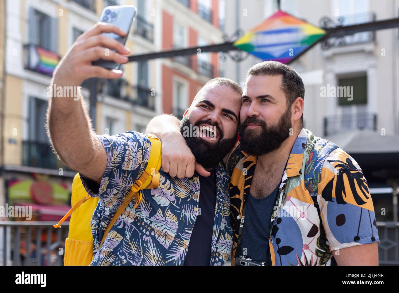 Zwei schwule Männer im Urlaub, die zusammen mit dem Mobiltelefon ein Foto während einer Stadtrundfahrt in einer Stadt machen. LGBT-Paare auf Reisen. Stockfoto
