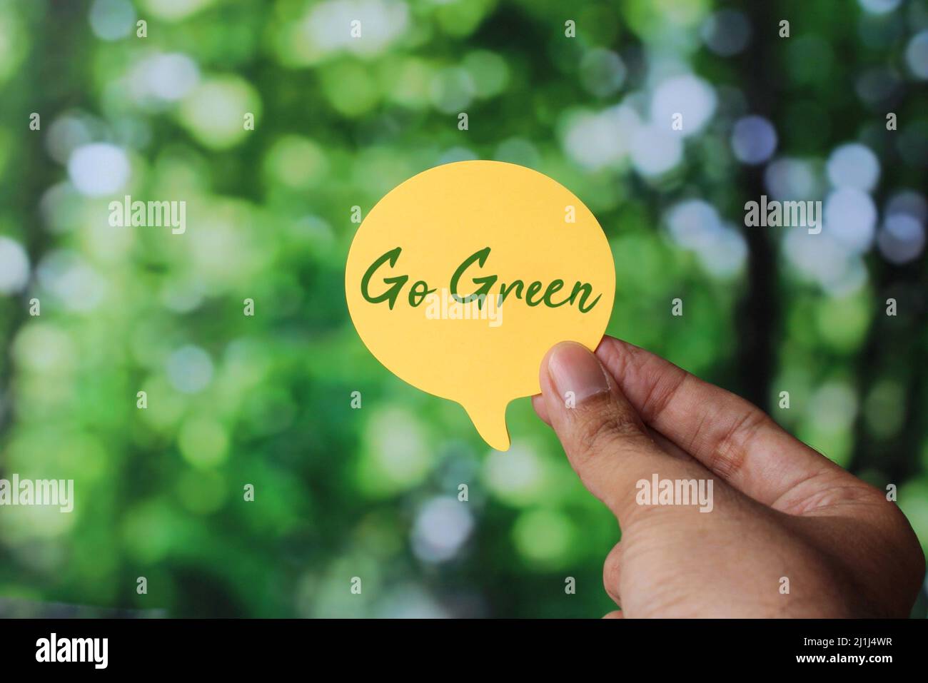 Hand halten Sprechblase mit Text Go Green auf Natur Bokeh Hintergrund. Tag der Erde, rette den Planeten Stockfoto