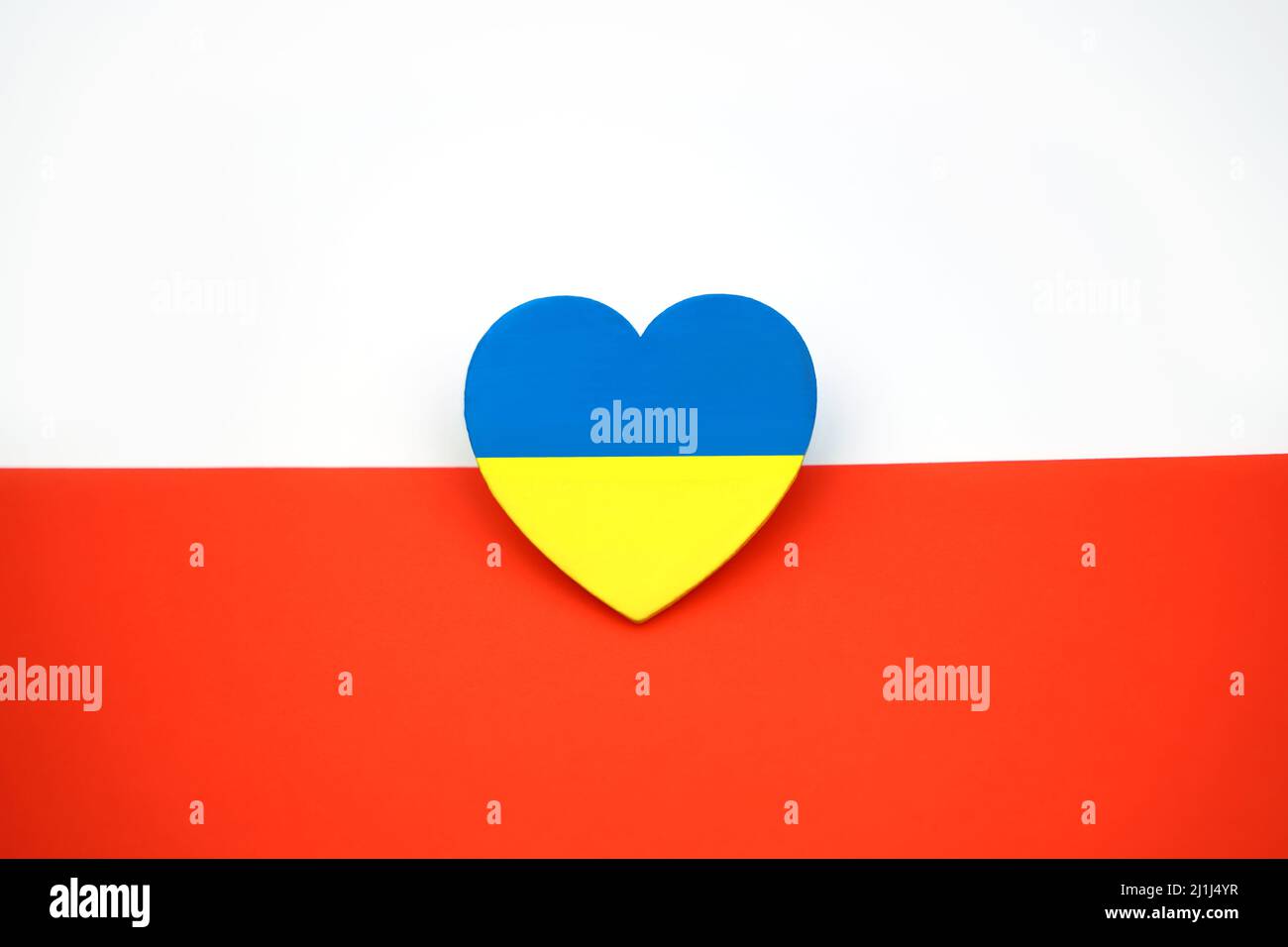 Die Flagge der Ukraine in Form des Herzens auf dem Hintergrund der Flagge Polens. Symbol der Solidarität und Unterstützung. Brüderliche Liebe Stockfoto