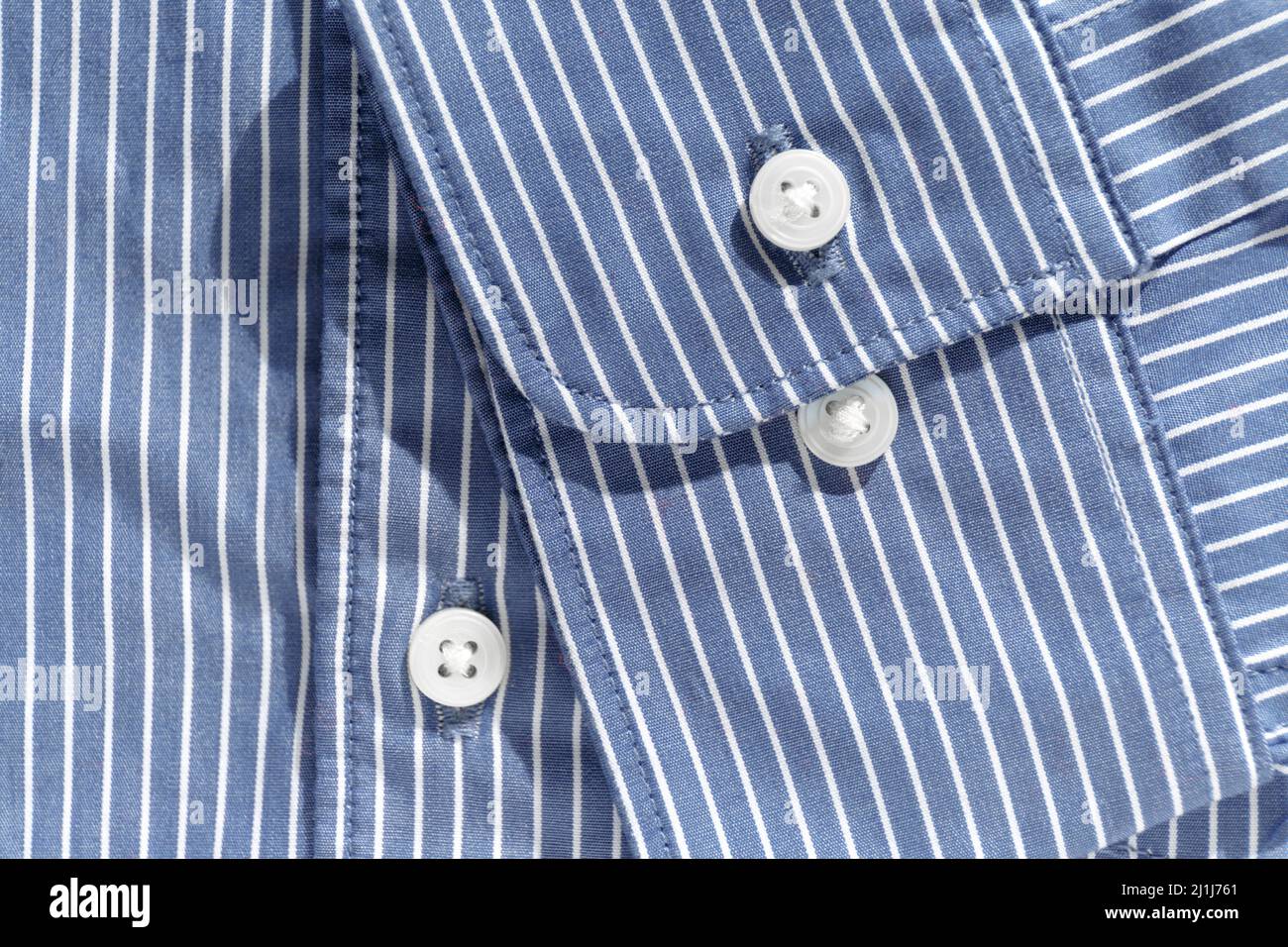 Manschetten. Ein zwei-Knopf-Bündchen auf einem blauen Hemd aus Bio-Baumwolle mit weißen Streifen. Details moderner Kleidung Stockfoto