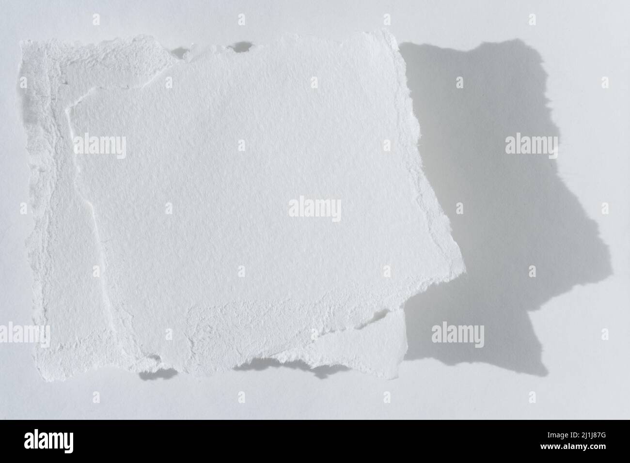 Zwei Stücke zerrissenes weißes Papier auf hellem Hintergrund. Die Papierseite für Reste ist isoliert Stockfoto