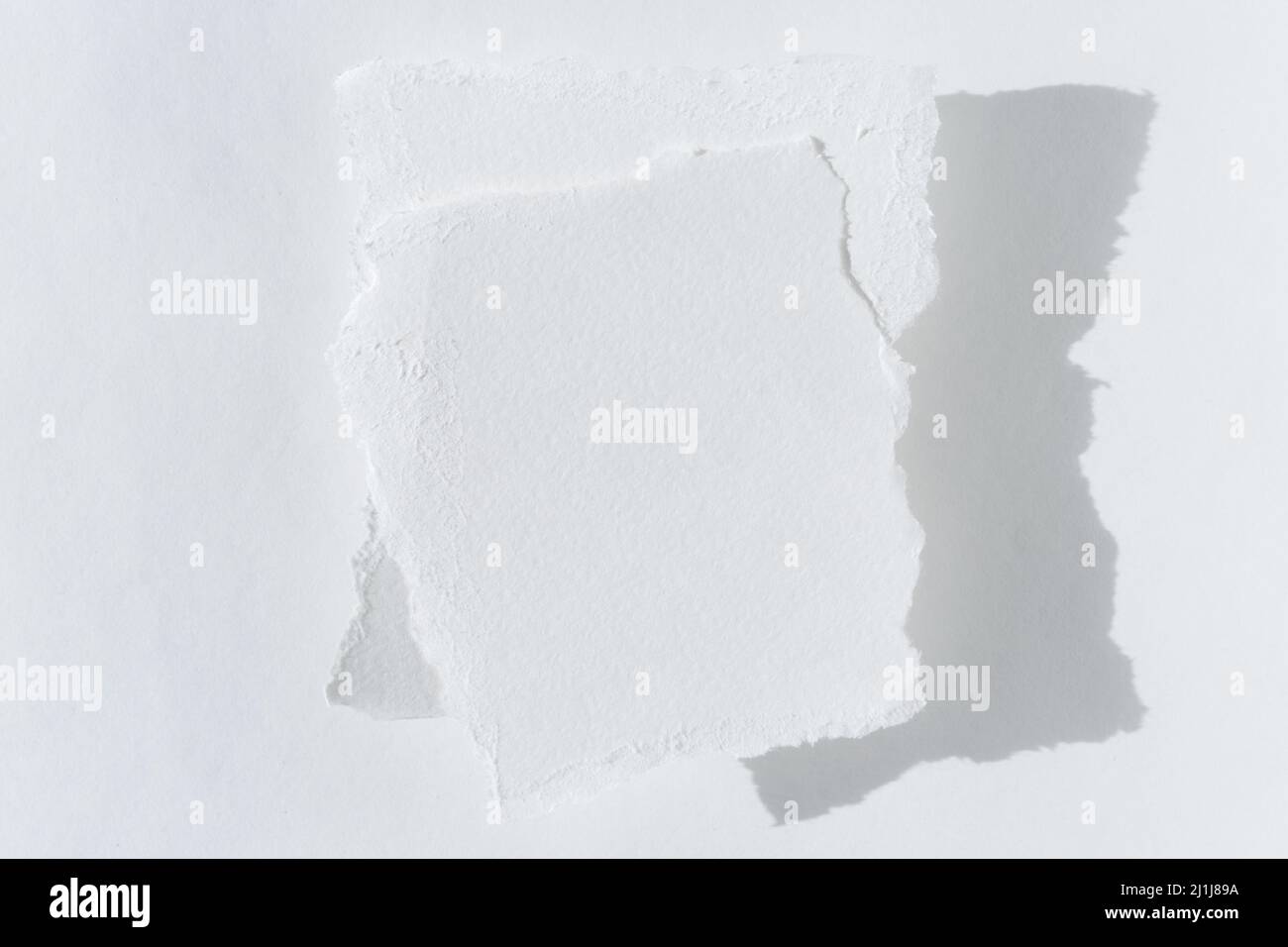 Zwei Stücke zerrissenes weißes Papier auf hellem Hintergrund mit einer Kopie des Textbereichs Stockfoto