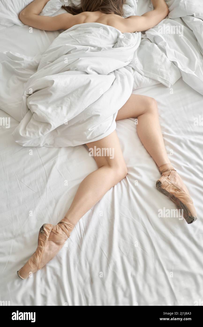 Frau in Spitzenschuhen, die auf einem leichten Bett ruht Stockfoto