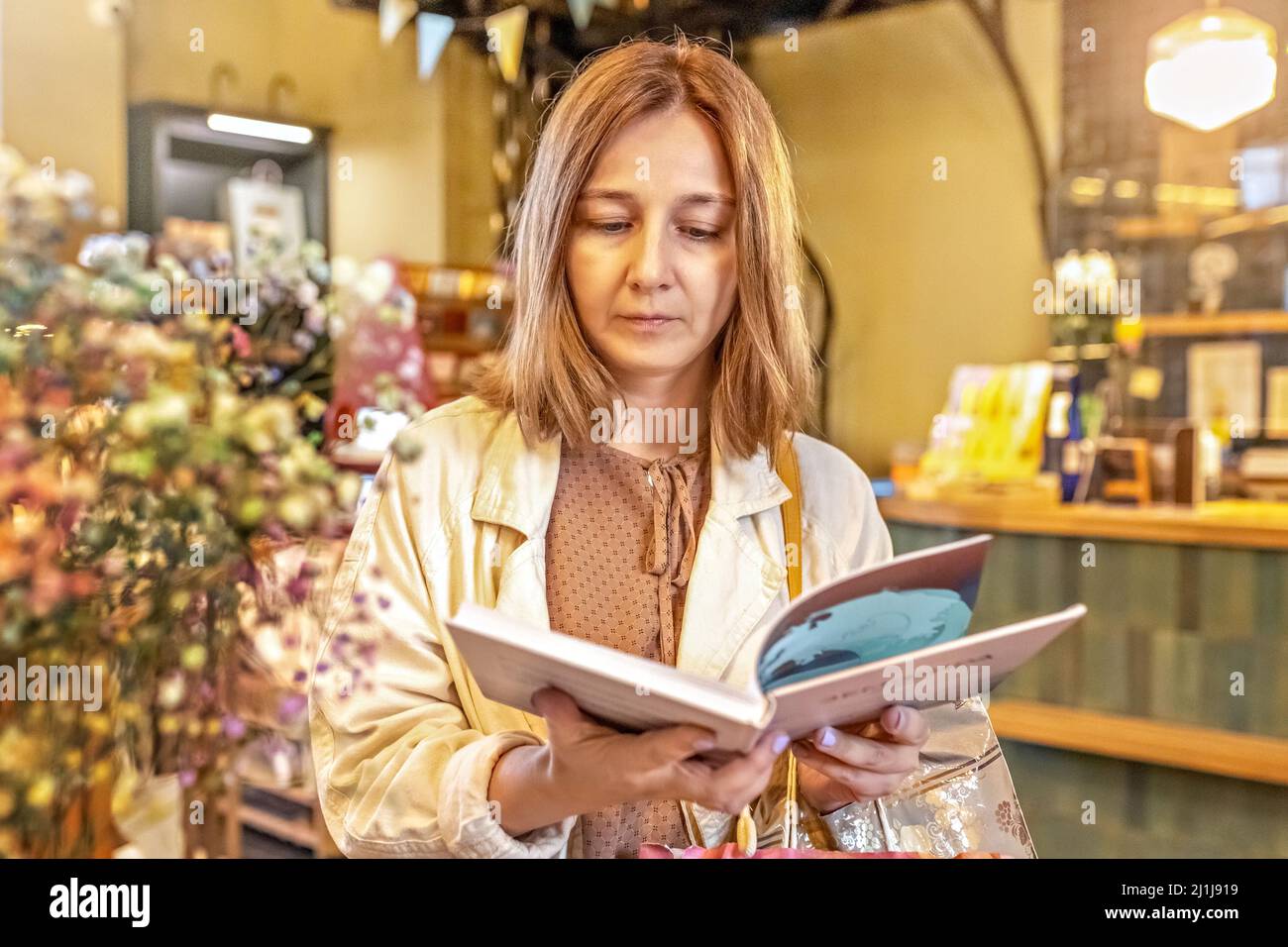 Eine junge Frau, eine Studentin, sitzt in der Bibliothek und liest ein Buch. College-Leben. Stockfoto