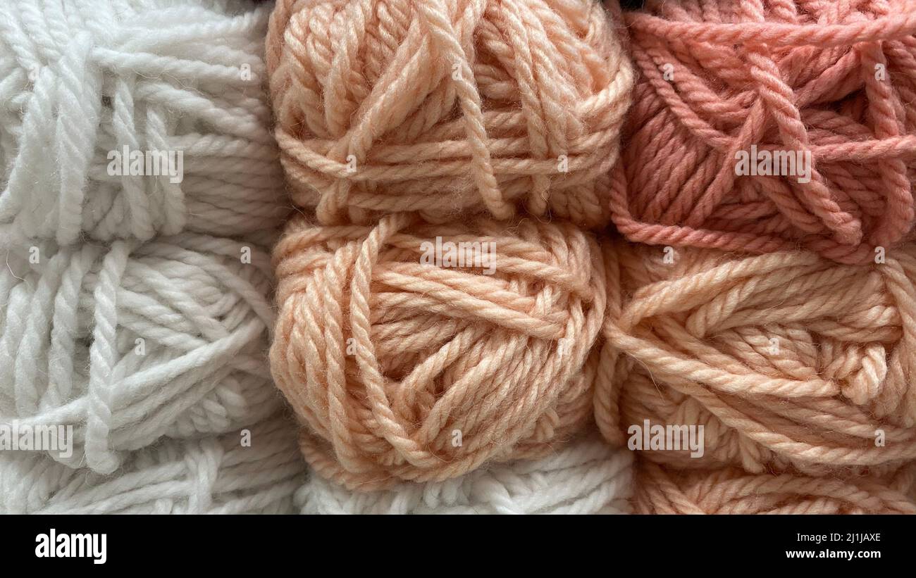 Wollgarn in Beige, Rosa und Weiß. Mehrfarbige Skeins aus Wolle in Nahaufnahme Stockfoto