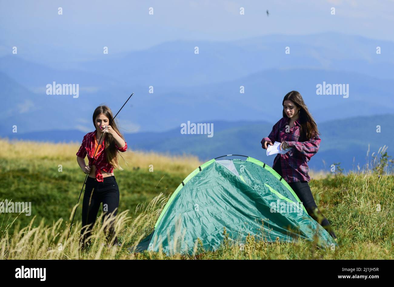 Vorübergehende Unterbringung. Konzept der Campingfähigkeiten. Camping und Wandern. Urlaub in den Bergen. Campingausflug. Es ist hilfreich, einen Partner für das Aufziehen des Zeltes zu haben. Mädchen Stockfoto