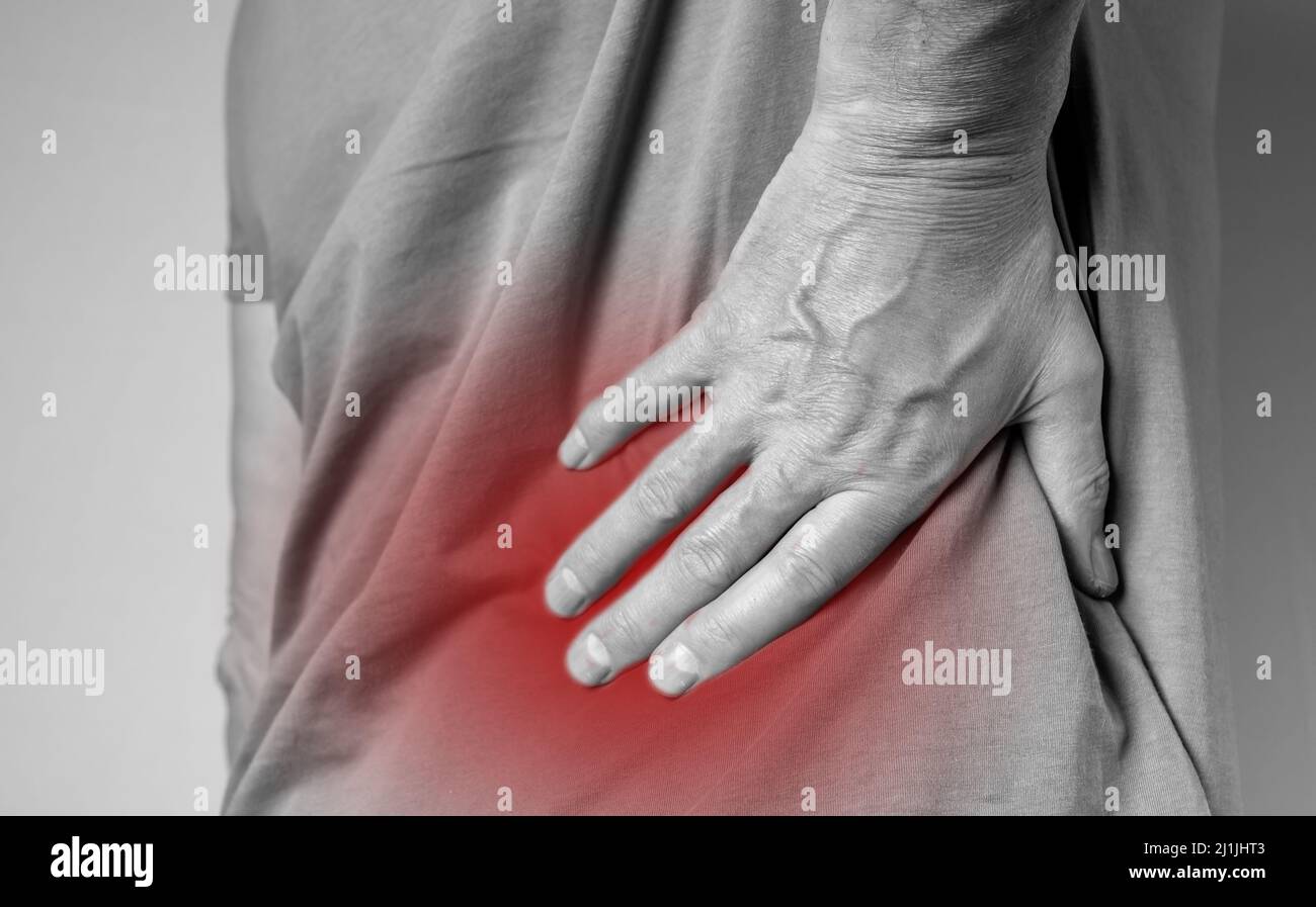 Schmerzen im unteren Rücken. Lumbago. Mann Hände mit roten schmerzhaften Punkt Nahaufnahme. Wirbelsäulenverletzung, gequetschte Muskeln. Gesundheitliche Probleme, Heilung Konzept. Hochwertige Fotos Stockfoto