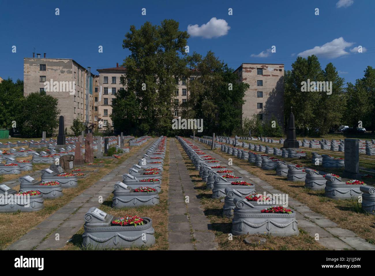 Sankt Petersburg, Russland - 18. Juli 2021: Reihen von Gräbern auf dem Militärfriedhof des Zweiten Weltkriegs vor dem Hintergrund eines Wohngebäudes Stockfoto