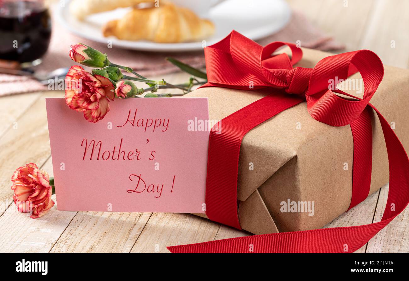 Happy Mothers Day Text auf einer Karte mit einem Geschenk und Nelkenblumen Stockfoto